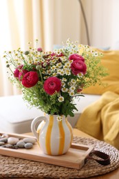 Photo of Beautiful ranunculus flowers and chamomiles in vase on table indoors