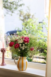 Photo of Beautiful ranunculus flowers and chamomiles in vase on windowsill indoors