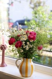 Photo of Beautiful ranunculus flowers and chamomiles in vase on windowsill indoors