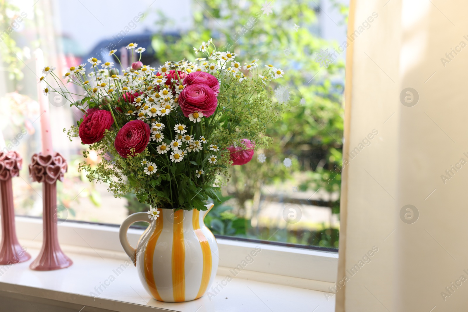 Photo of Beautiful ranunculus flowers and chamomiles in vase on windowsill indoors