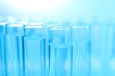 Many glass test tubes on light blue background, closeup