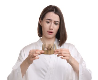 Emotional woman holding comb with lost hair on white background. Alopecia problem