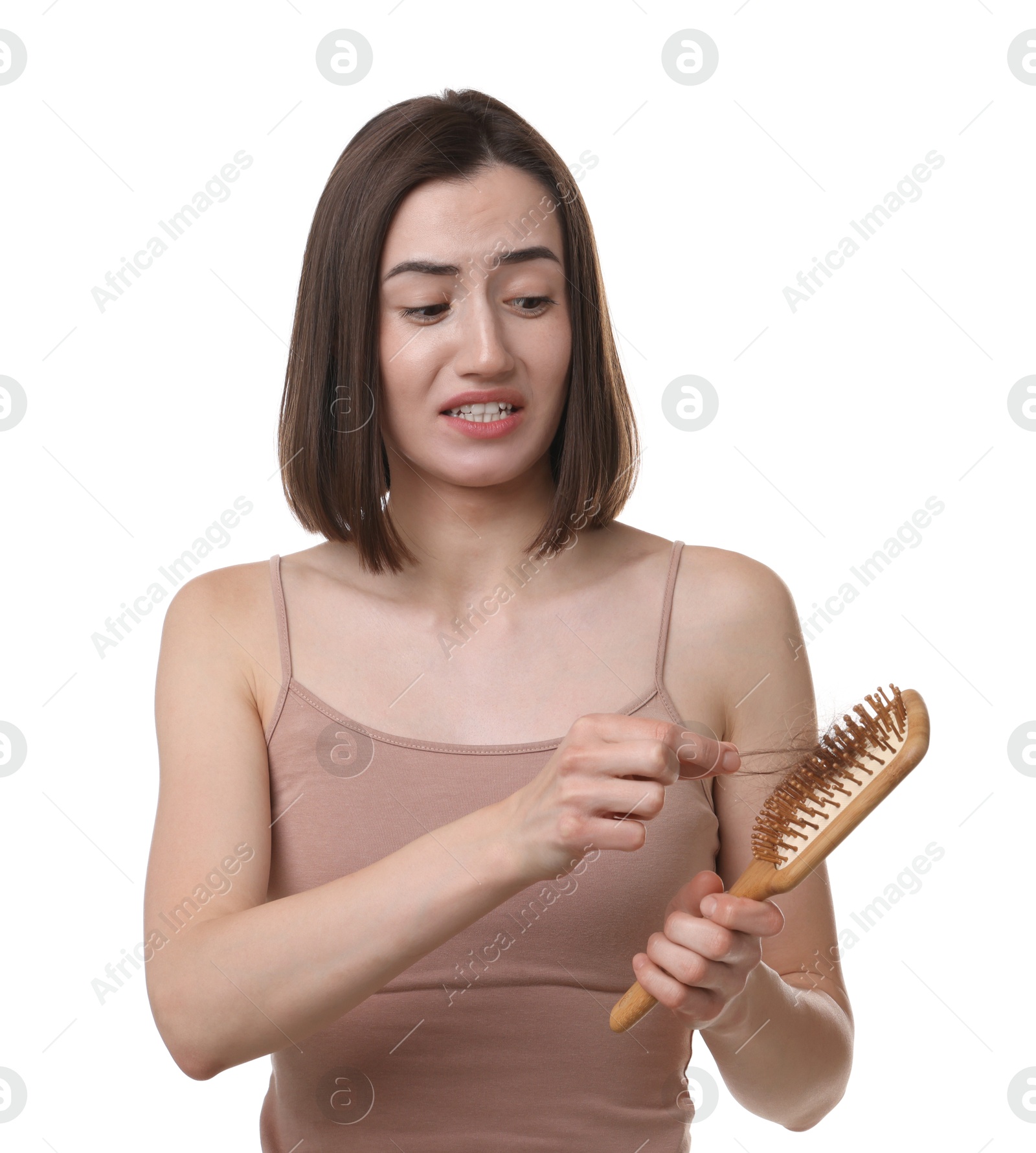 Photo of Emotional woman holding brush with lost hair on white background. Alopecia problem