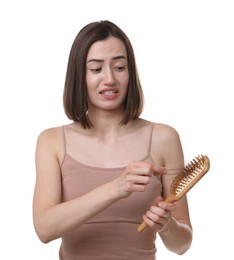 Photo of Emotional woman holding brush with lost hair on white background. Alopecia problem