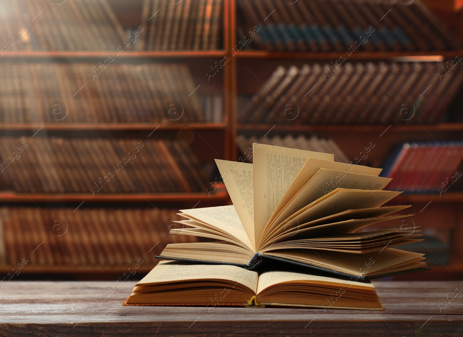 Image of Books on wooden table against full shelves in library