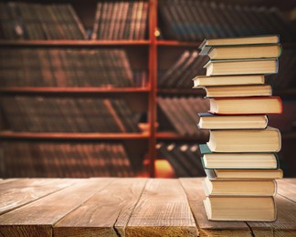 Image of Lots of books on wooden table against shelves in library. Space for text