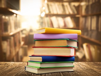 Lots of books on wooden table against full shelves in library