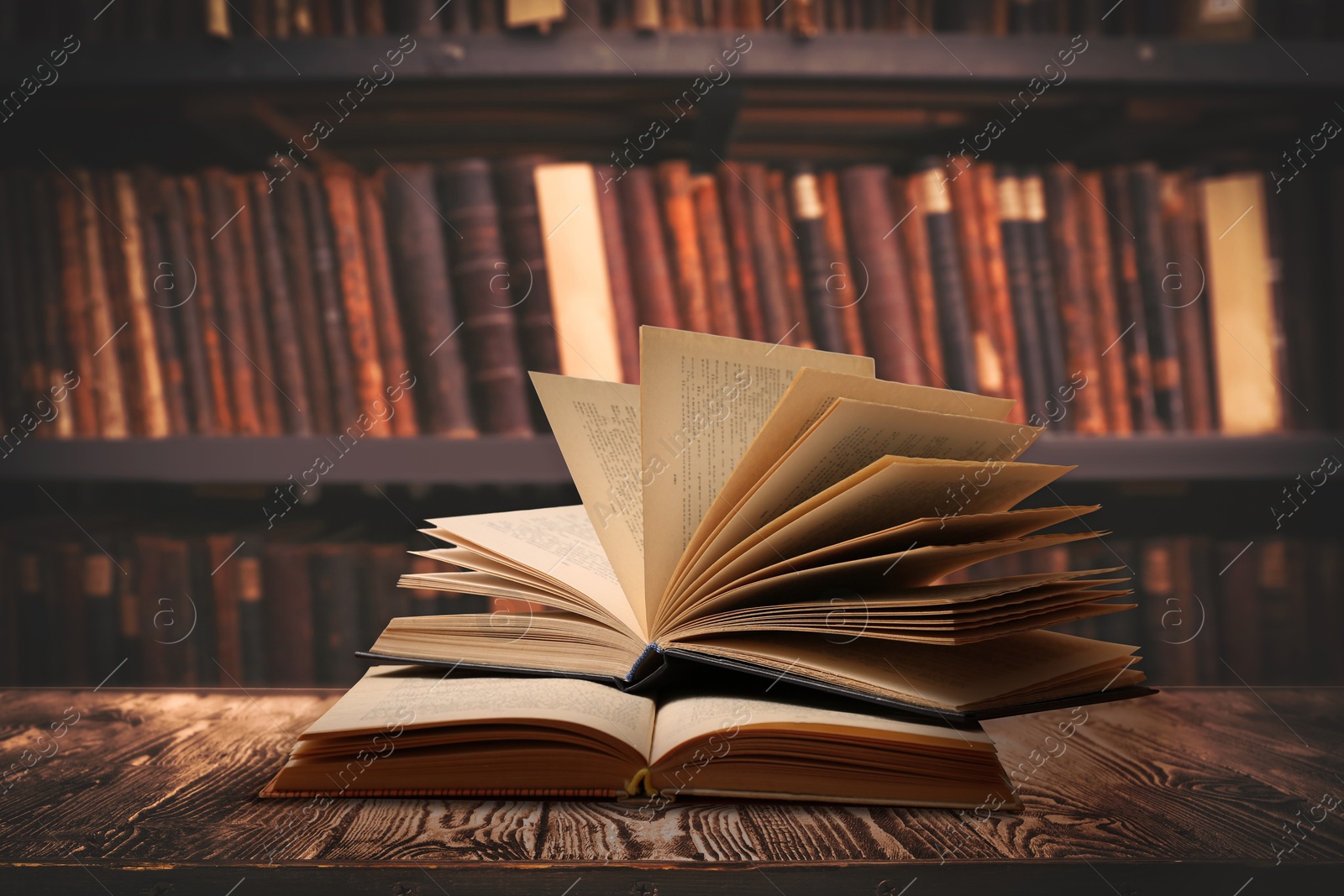 Image of Books on wooden table against full shelves in library