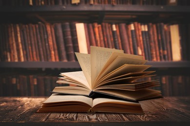 Books on wooden table against full shelves in library