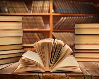 Image of Lots of books on wooden table against full shelves in library