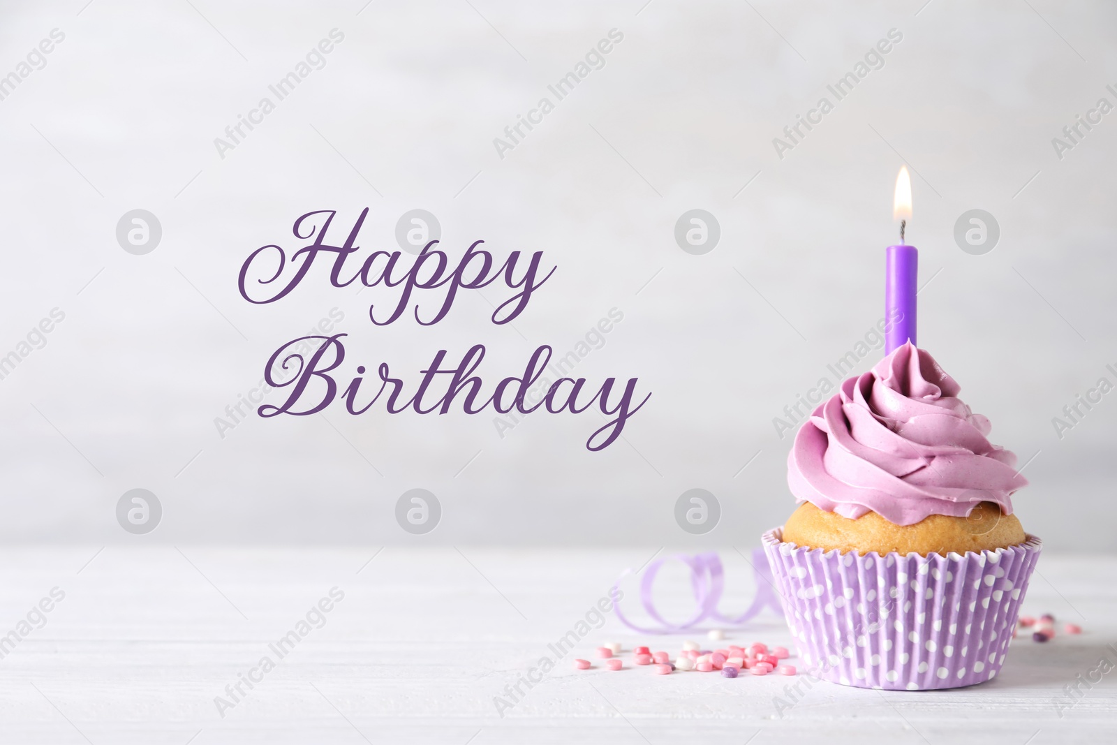 Image of Happy Birthday. Cupcake with candle on table against light background