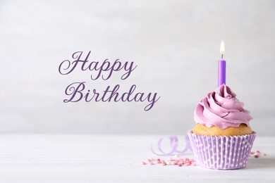 Image of Happy Birthday. Cupcake with candle on table against light background