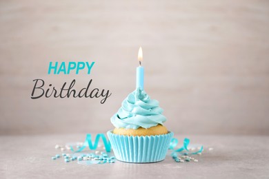 Image of Happy Birthday. Cupcake with candle on table against light background