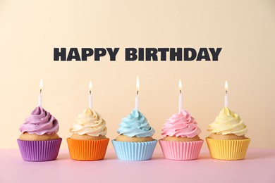 Image of Happy Birthday. Colorful cupcakes with candles on beige background