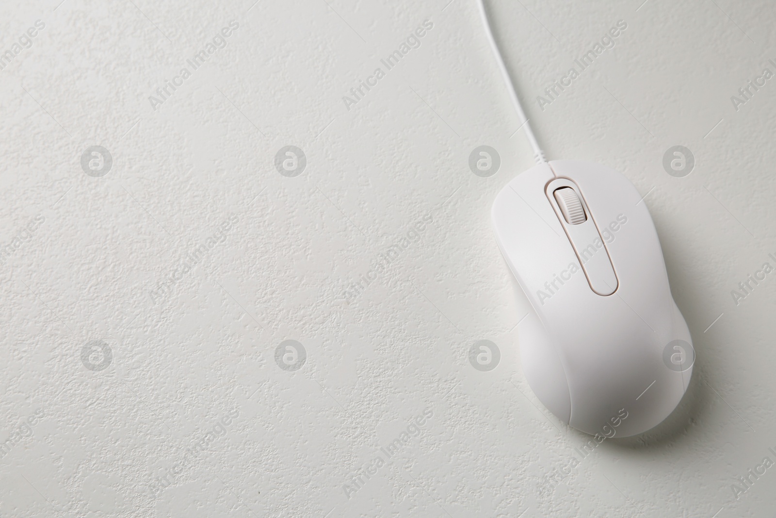 Photo of Wired mouse on light textured table, top view. Space for text
