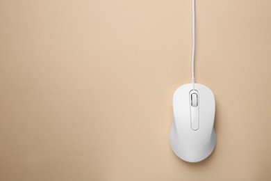One wired mouse on beige background, top view. Space for text