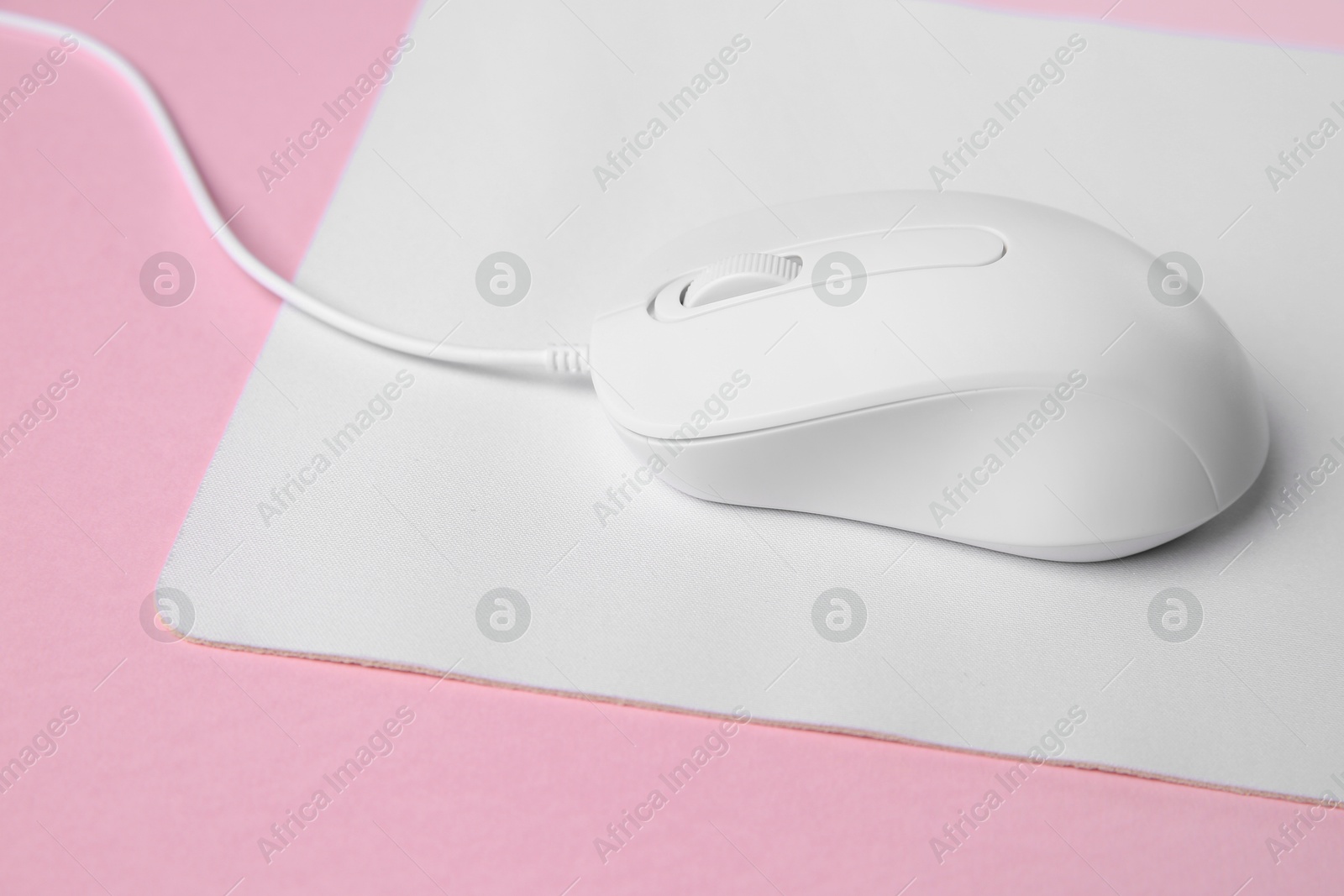 Photo of One wired mouse with mousepad on pink background, closeup