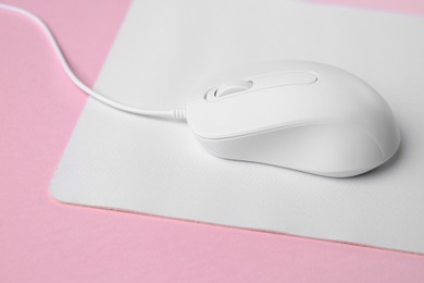 One wired mouse with mousepad on pink background, closeup