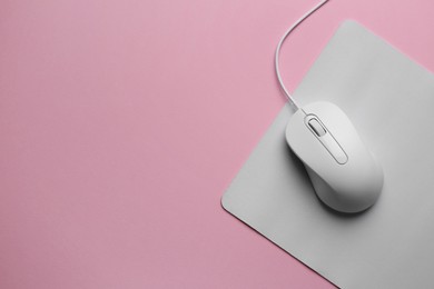 Wired mouse with mousepad on pink background, top view. Space for text