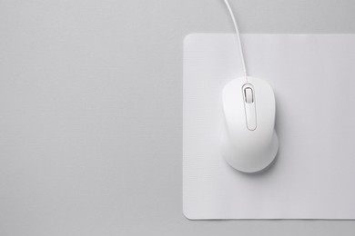 Wired mouse with mousepad on grey background, top view. Space for text