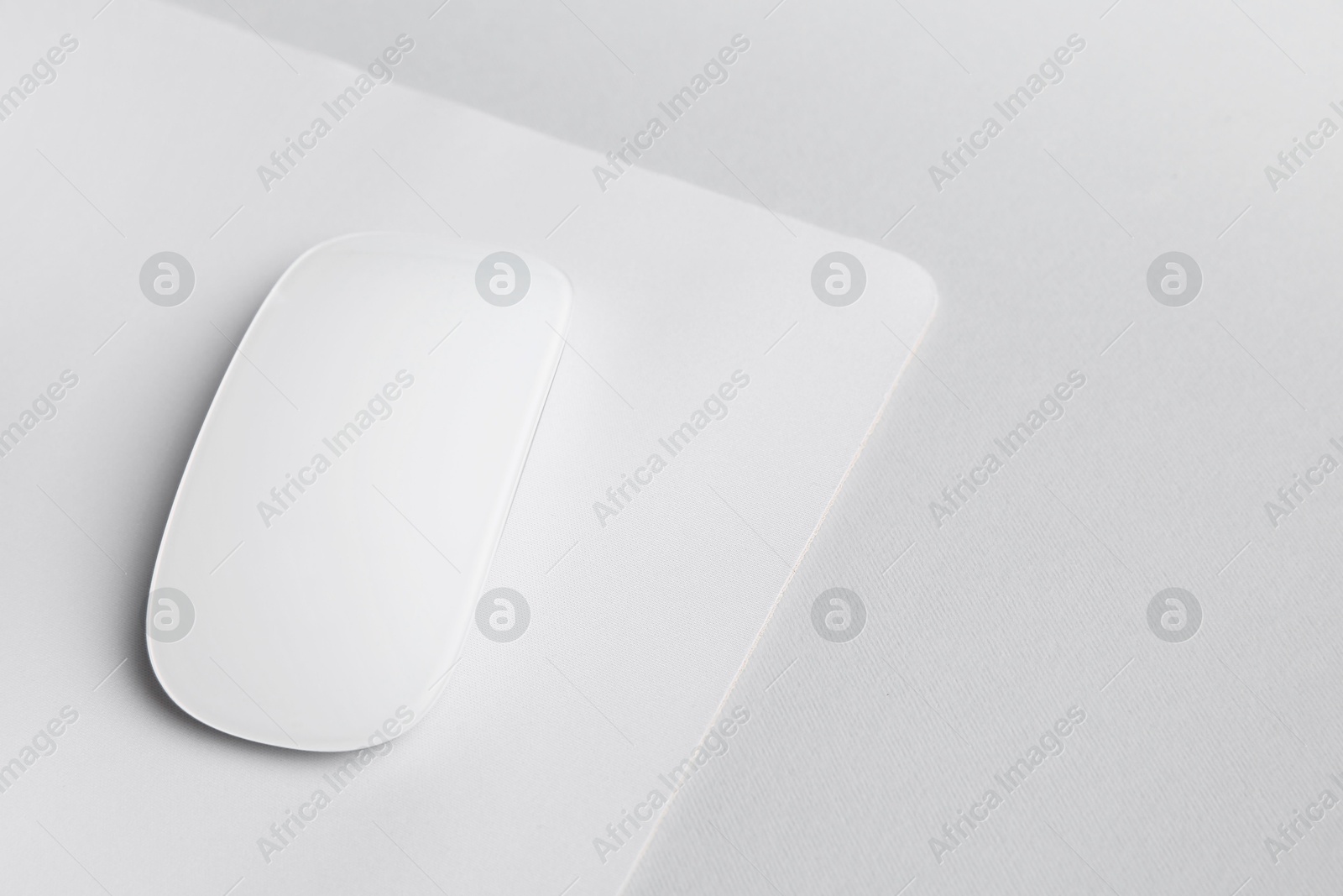 Photo of One wireless mouse with mousepad on grey background, closeup. Space for text