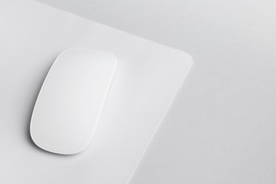 Photo of One wireless mouse with mousepad on grey background, closeup. Space for text