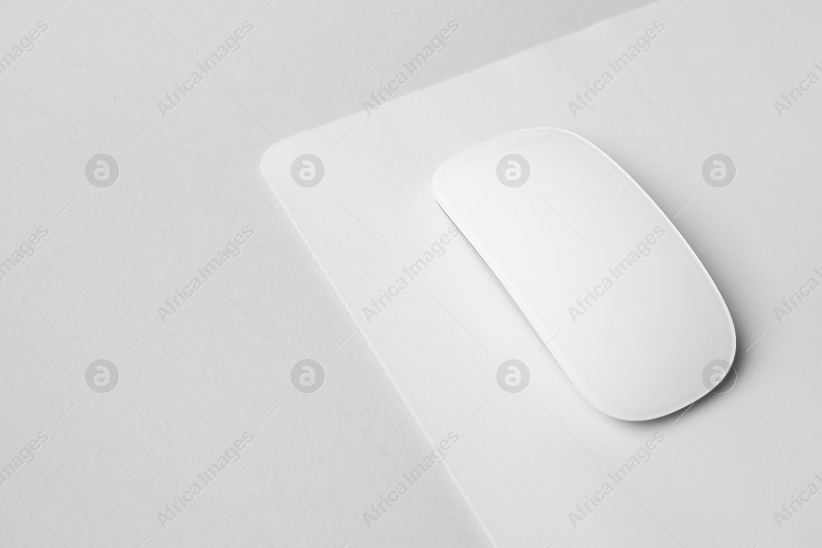 Photo of One wireless mouse with mousepad on grey background, closeup. Space for text