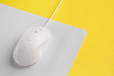 One wired mouse with mousepad on yellow background, closeup