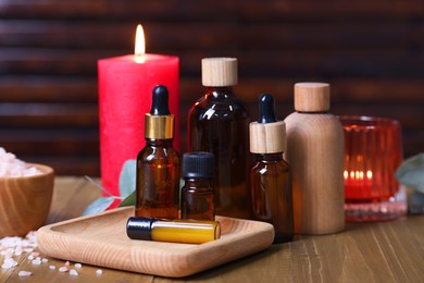 Photo of Different aromatherapy products and burning candles on wooden table