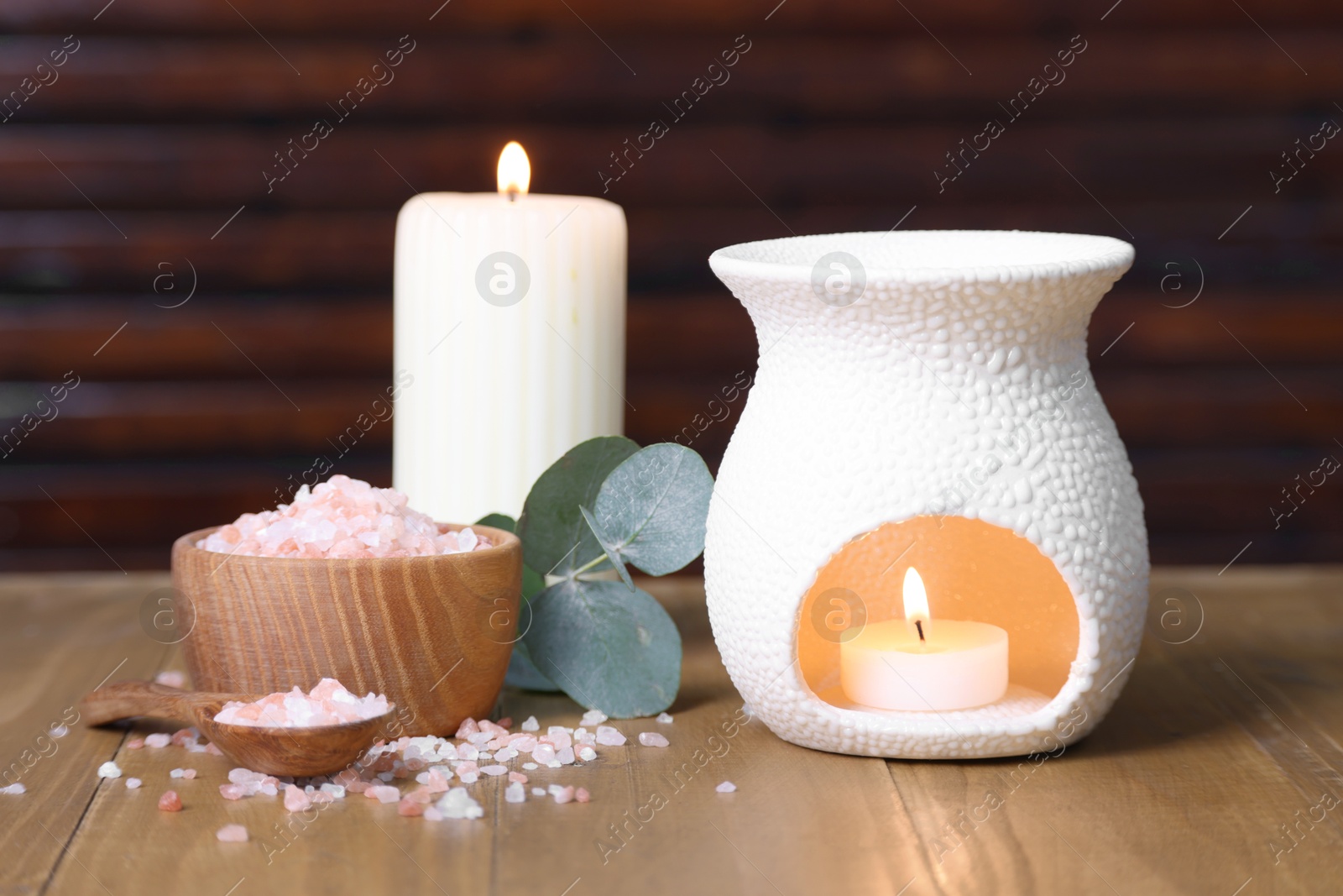 Photo of Different aromatherapy products, burning candles and eucalyptus leaves on wooden table