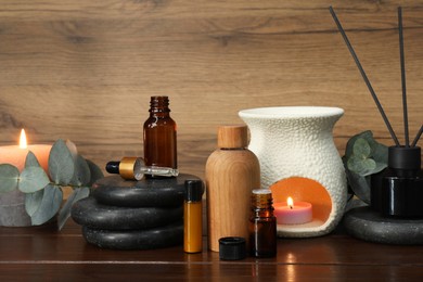 Photo of Aromatherapy products, burning candles and eucalyptus leaves on wooden table