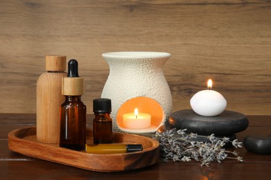 Aromatherapy products, burning candles and lavender on wooden table