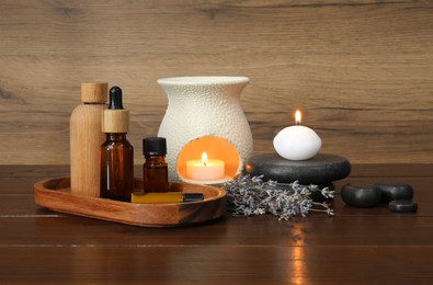 Photo of Aromatherapy products, burning candles and lavender on wooden table