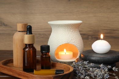 Aromatherapy products, burning candles and lavender on wooden table
