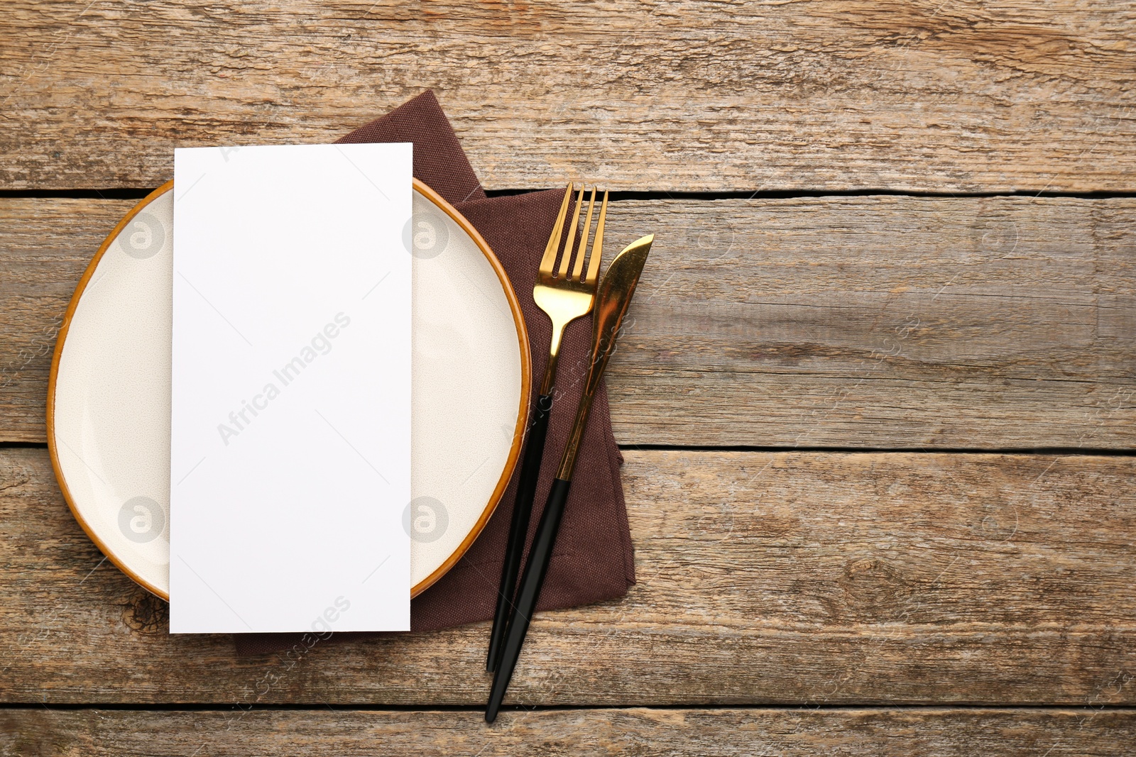 Photo of Empty menu, cutlery, plate and napkin on wooden table, top view. Mockup for design