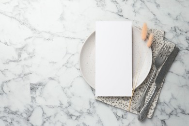 Photo of Empty menu, cutlery, plate, napkin and dry spikes on white marble table, top view. Mockup for design