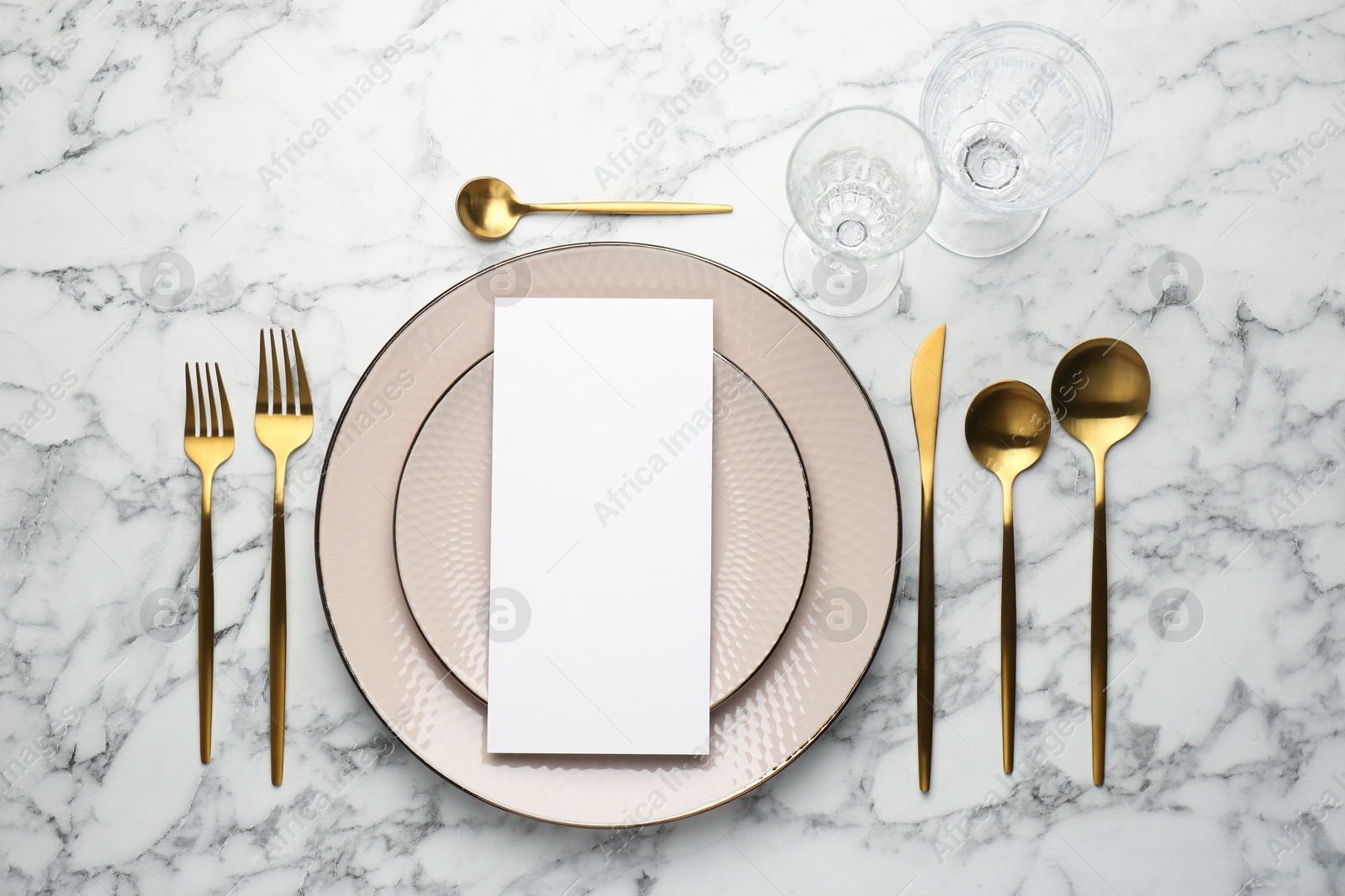 Photo of Empty menu, cutlery, glasses and plates on white marble table, flat lay. Mockup for design