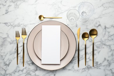 Empty menu, cutlery, glasses and plates on white marble table, flat lay. Mockup for design