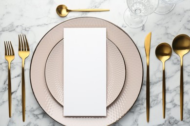 Photo of Empty menu, cutlery, glass and plates on white marble table, flat lay. Mockup for design