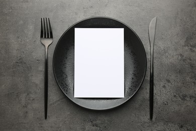 Photo of Empty menu, plate and cutlery on grey table, top view. Mockup for design