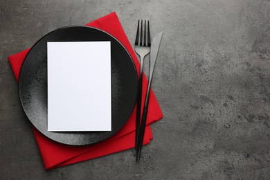 Empty menu, plate, cutlery and napkin on grey table, top view. Mockup for design