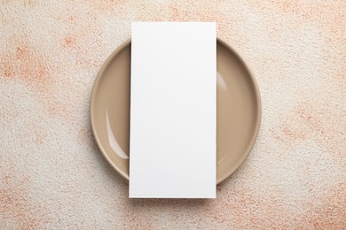 Photo of Empty menu and plate on color textured table, top view. Mockup for design