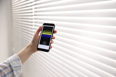 Photo of Woman using smartphone to adjust window blinds indoors, closeup. Space for text