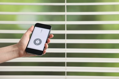 Photo of Woman using smartphone to adjust window blinds indoors, closeup. Space for text