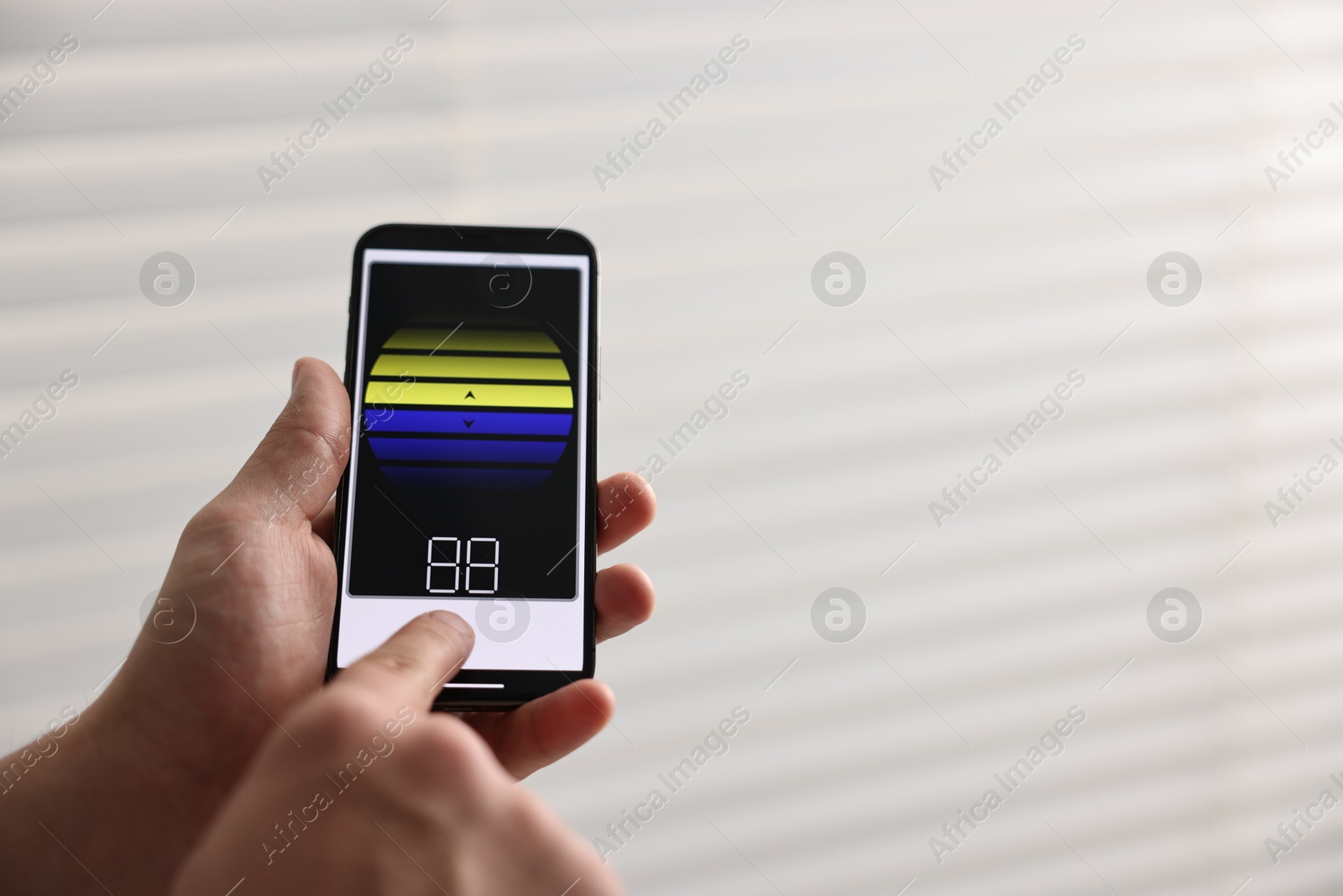 Photo of Man using phone to adjust window blinds indoors, closeup. Space for text