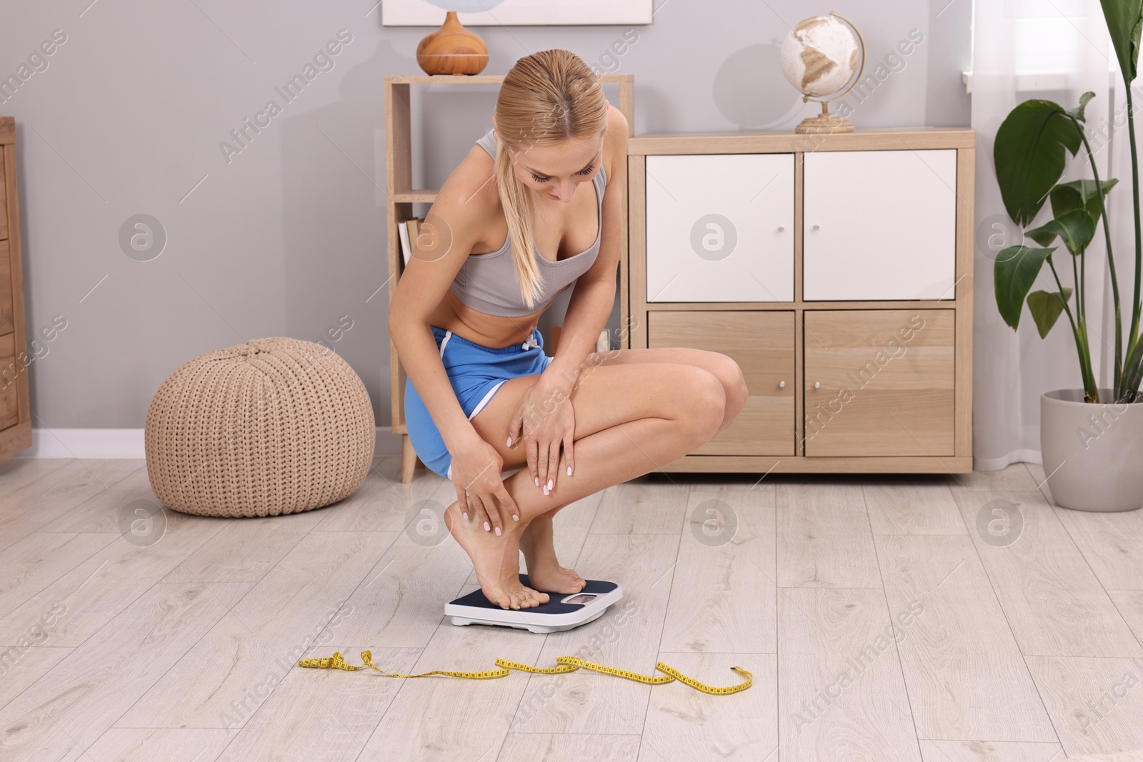 Photo of Woman measuring weight on floor scale at home