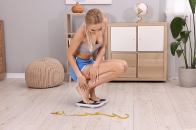 Photo of Woman measuring weight on floor scale at home