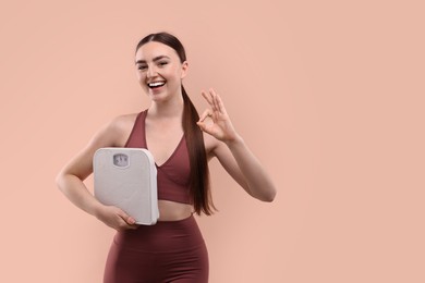 Happy woman with floor scale showing ok gesture on beige background. Space for text