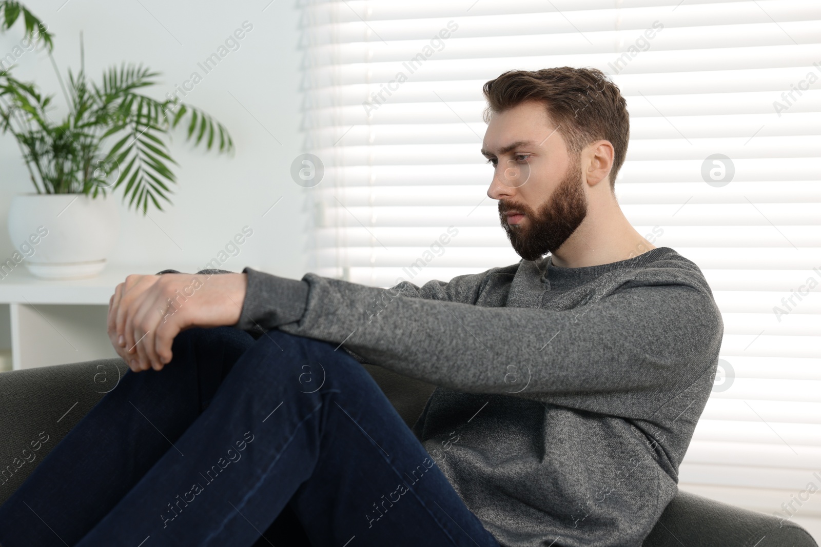 Photo of Loneliness concept. Sad man sitting on sofa at home