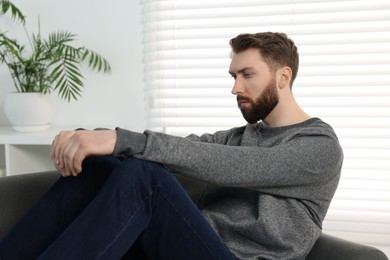 Photo of Loneliness concept. Sad man sitting on sofa at home